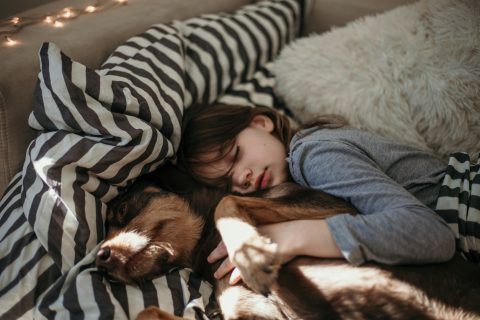 Little girl and her dog sleeping in the bed